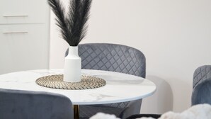 A modern living room with a round white table, a grey upholstered chair, and a white sofa.