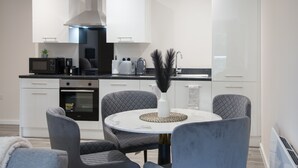 A modern kitchen with white cabinets, a black microwave, and a round dining table with four chairs.
