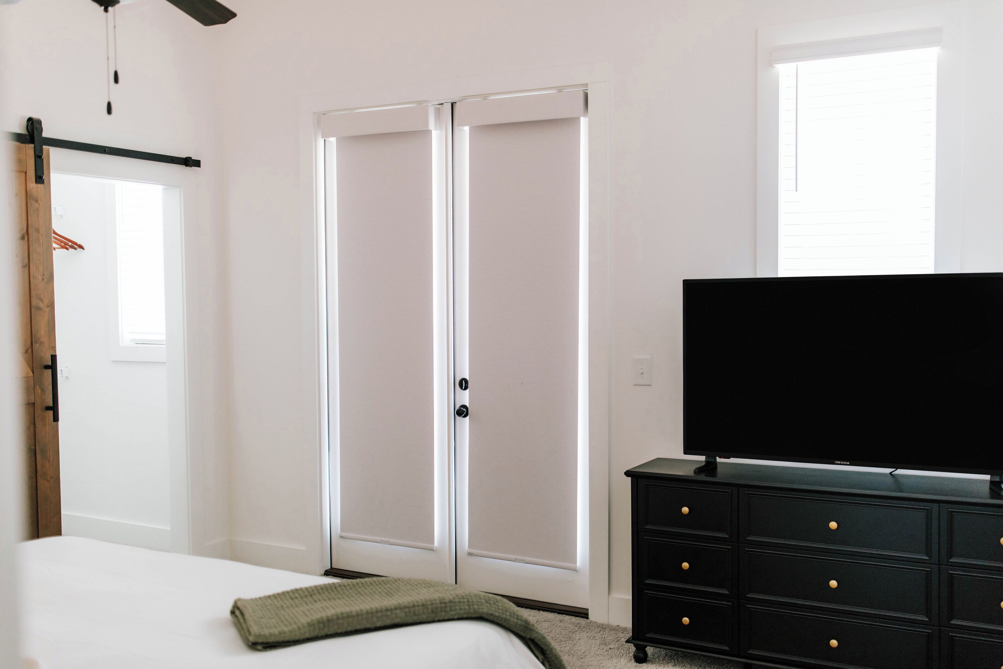 A bedroom with a bed, a wardrobe, a dresser, and a television.