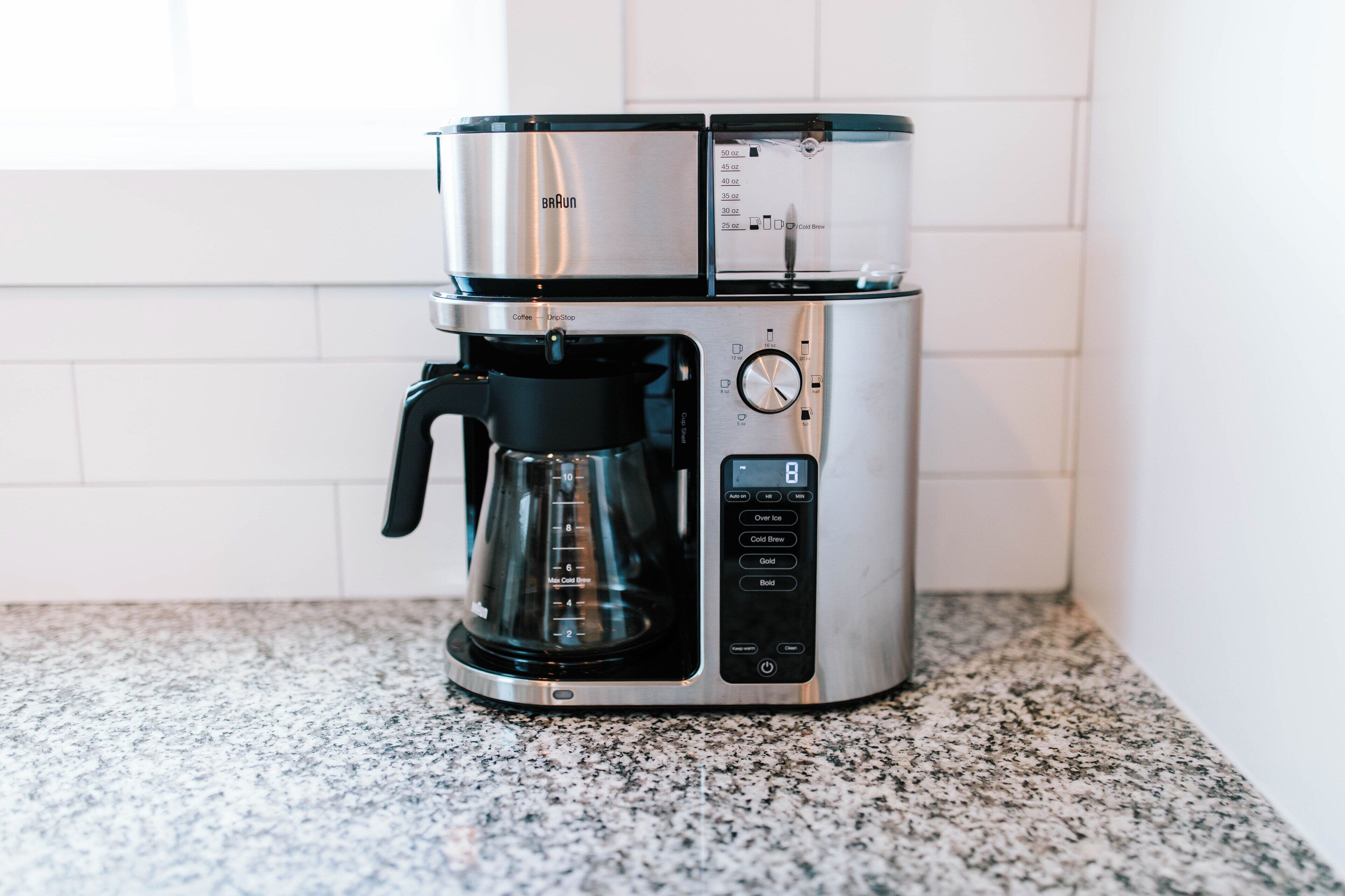 Una màquina de cafè amb pantalla digital i un recipient per a caf è a la part superior, damunt d'una superfície de granit.