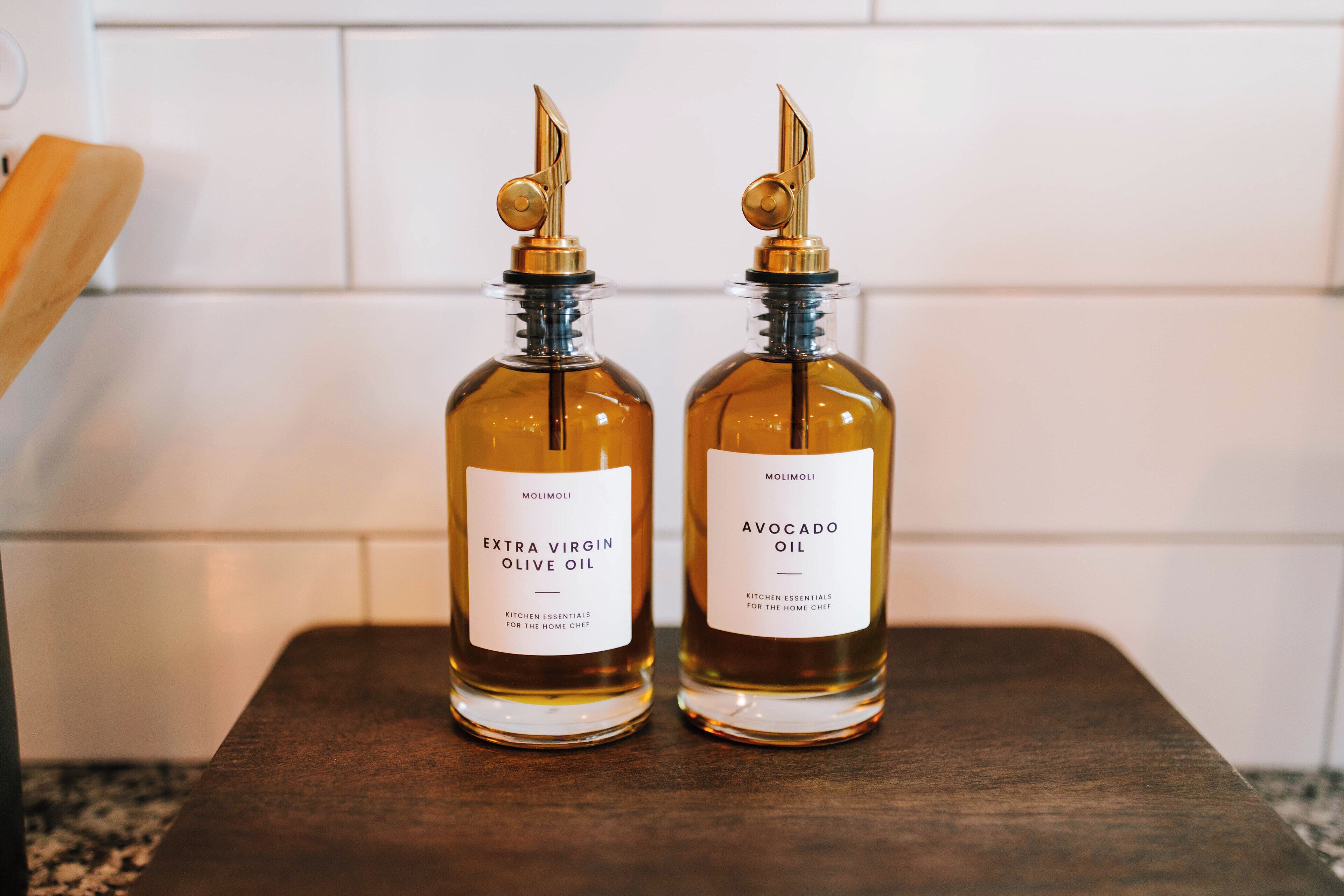 Two bottles of Molimoli Extra Virgin Olive Oil and Avocado Oil on a wooden surface.