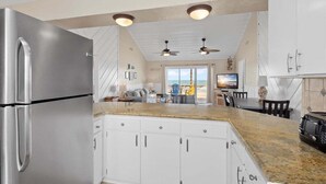 Eine moderne Küche mit Edelstahlgeräten, weißen Schränken, Granitarbeitsplatten und einem Essbereich mit Aussicht.