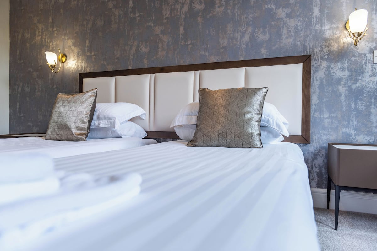 A hotel room with a large bed, two nightstands, and a wall-mounted light fixture.