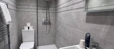 Un baño moderno con ducha, inodoro y lavamanos.