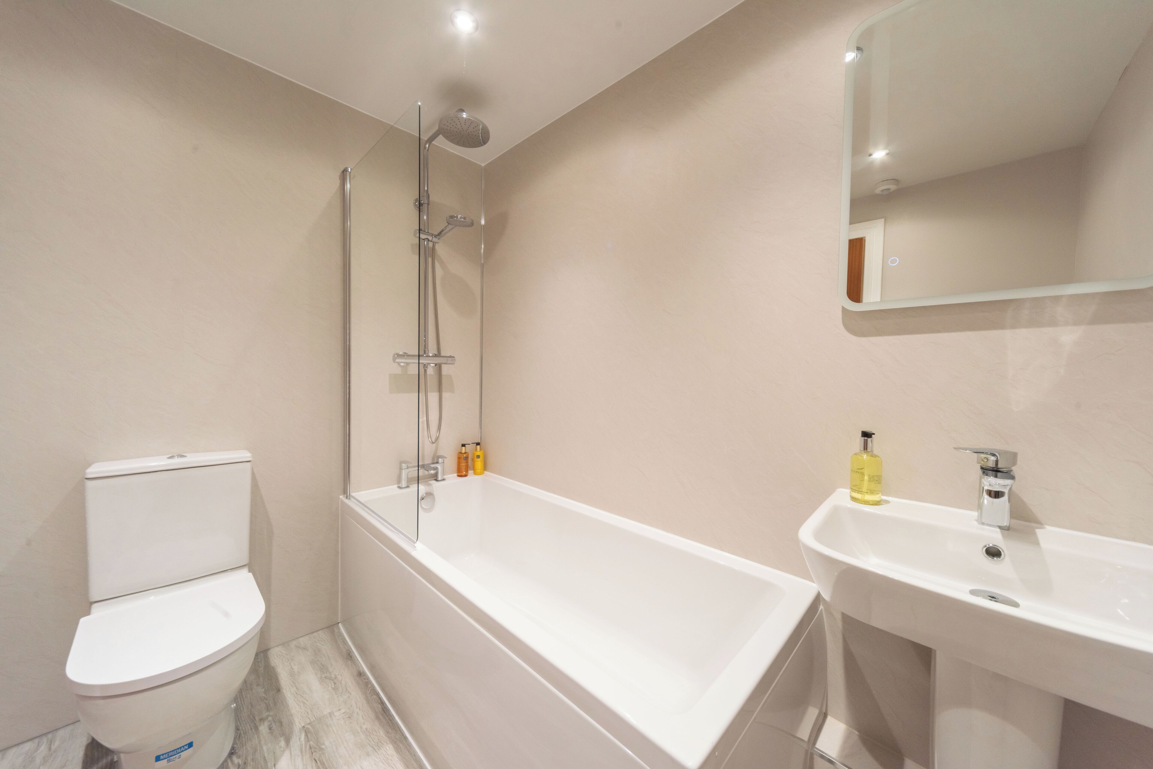A modern bathroom with a white bathtub, a toilet, and a sink with a mirror.