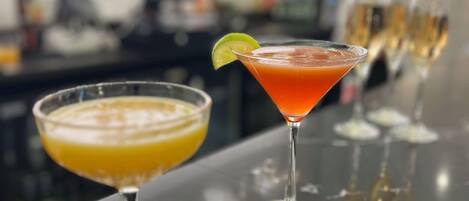 Three cocktails on a bar counter with a blurred background of a bar area.