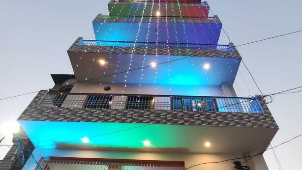 A multi-story building with a balcony decorated with colorful drapes and floral arrangements.
