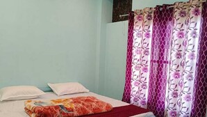 A bedroom with a bed, a ceiling fan, and patterned curtains.
