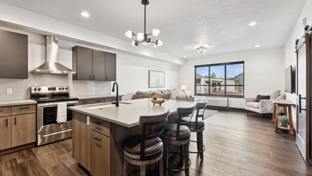 A modern kitchen with a central island, stainless steel appliances, and a large window providing a view of the outdoors.