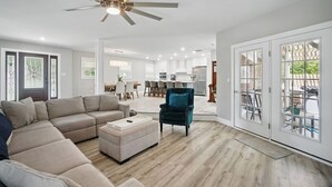 A spacious living room with a sectional sofa, a teal armchair, and a ceiling fan. - House with Hot tub, close to Marina, in a Golf Course Community (Hertford)