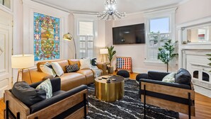 A living room with a sofa, coffee table, and a fireplace. - Amazing Location! Short North Victorian Oasis 5-bedroom w Hot Tub and Peleton (Columbus)