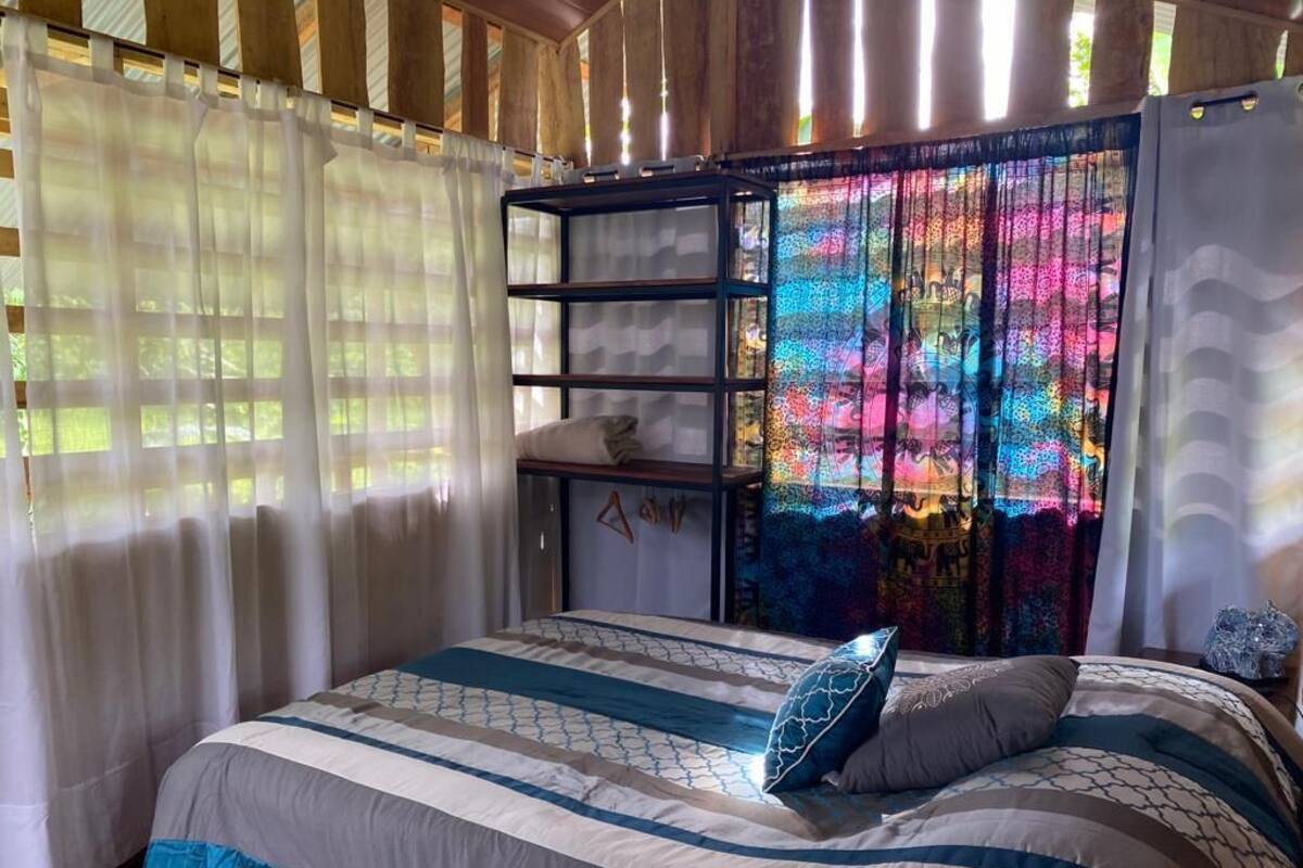 Un dormitorio con cama, una estantería y una cortina de colores.