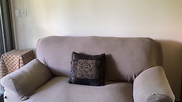 A living room with a grey sofa, a decorative pillow, and a large abstract painting on the wall.