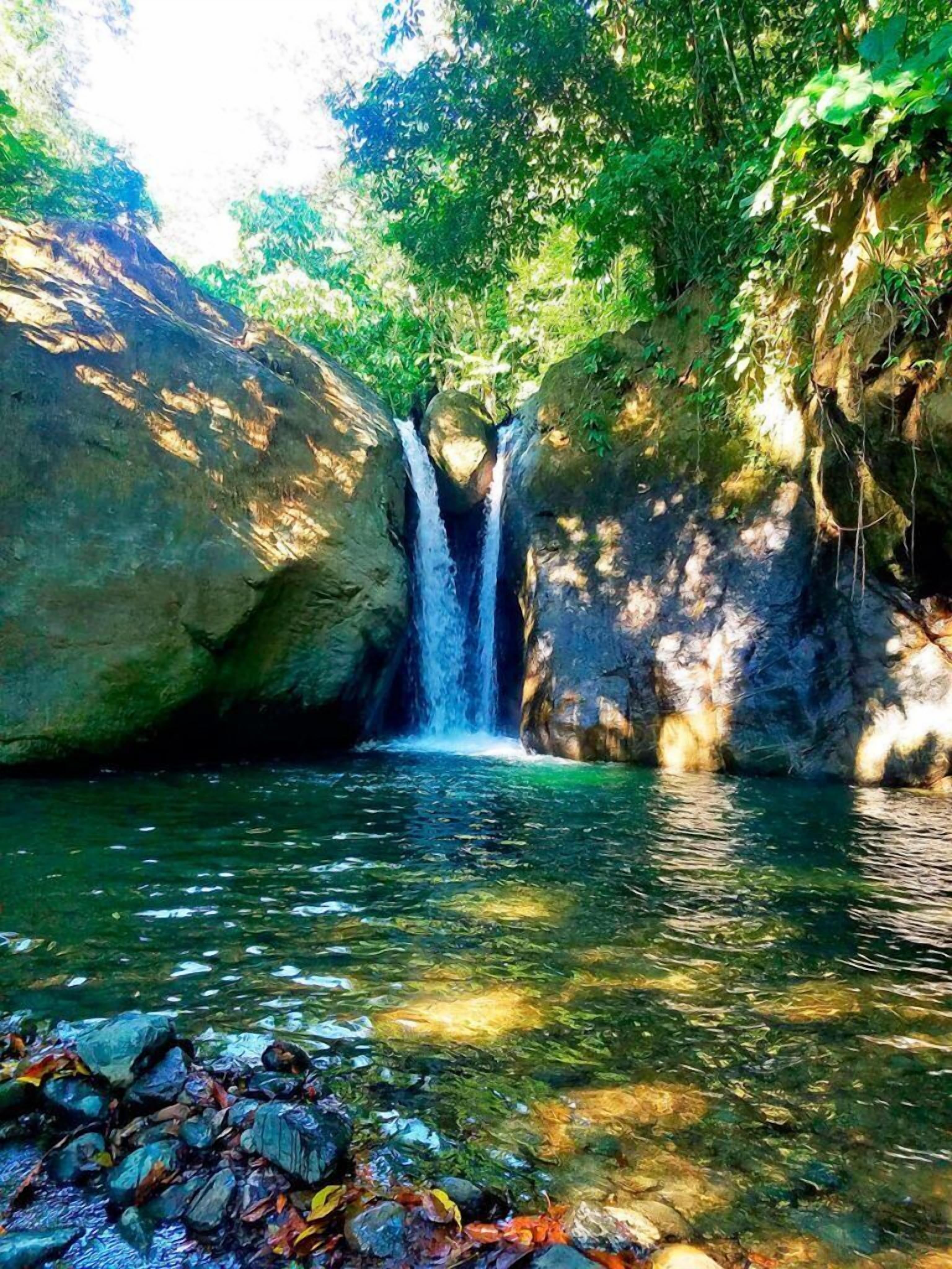 A waterfall in a forested area with a clear stream at the base.