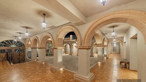 A spacious interior with high ceilings, arched columns, and a tiled floor. - Hotel Suites Cristal Casa Vacacional (San Miguel de Allende)