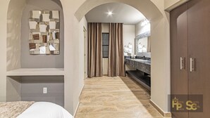 A hotel room with a bed, a vanity with a mirror, a shower area, and a wardrobe. - Hotel Suites Cristal Casa Vacacional (San Miguel de Allende)