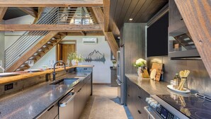 A modern kitchen with a granite countertop, stainless steel appliances, and a wooden staircase. - Newly Built Sauna Hot Tub Cold Punge Lazy River Glamp-house by Avantstay (La Pine)