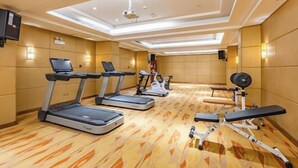 Un gimnasio con cintas de correr, bicicletas estáticas y equipo de levantamiento de pesas.