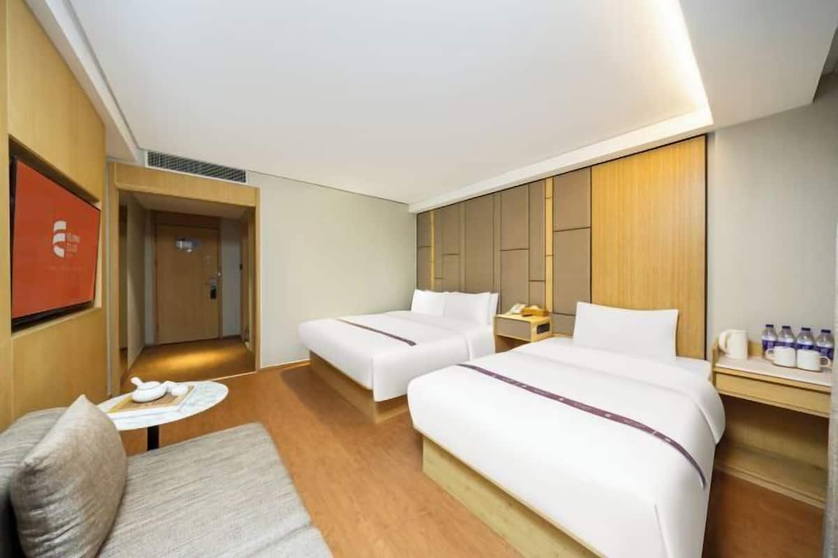 Habitació d'hotel amb dos llits, un petit sofà, una taula amb tetera i un mini bar.