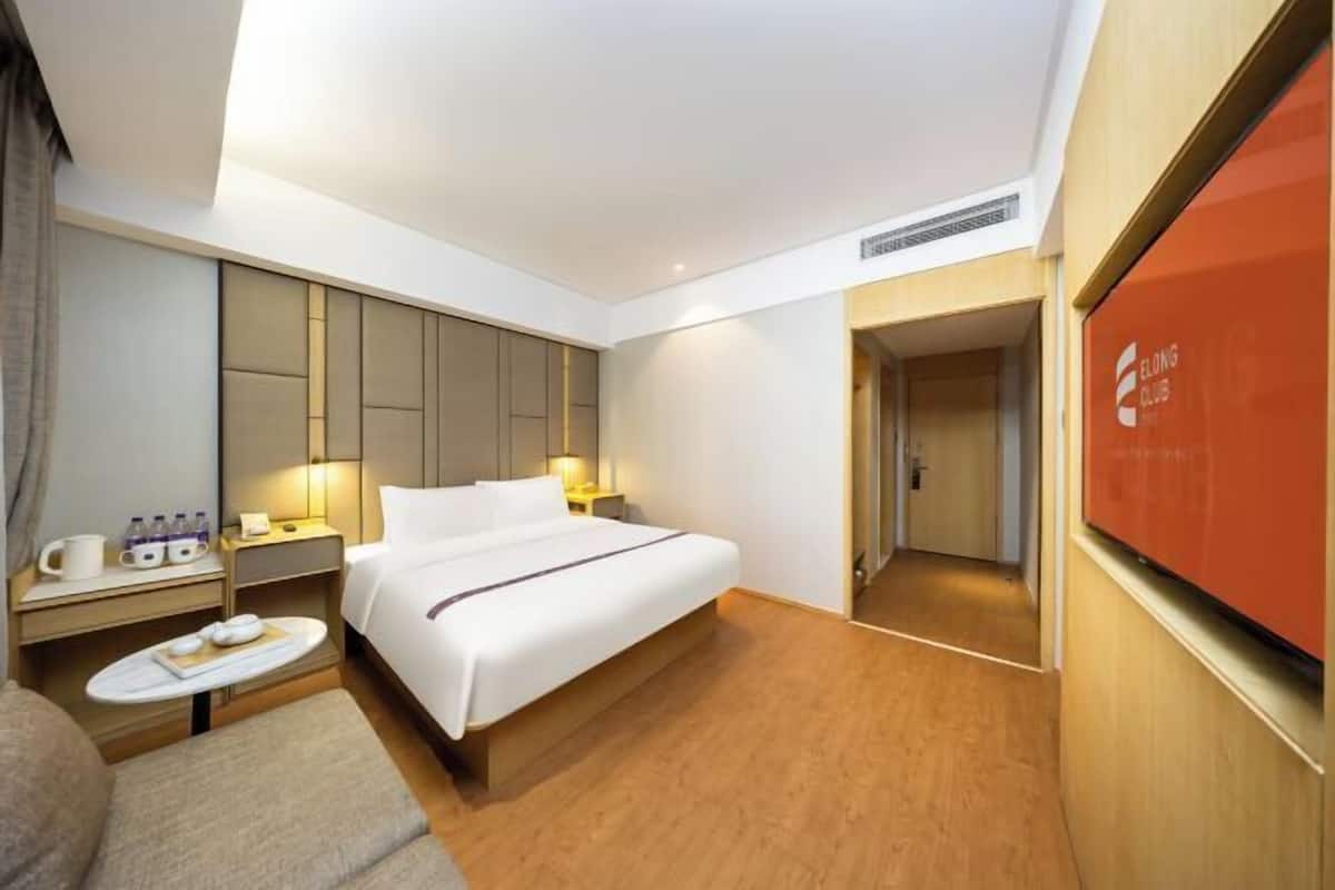 Habitació d'hotel amb llit, taules de nit, zona de seients i televisió.