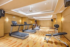 Une salle de sport équipée de tapis de course, d’un banc de musculation et d’autres appareils d’exercice.