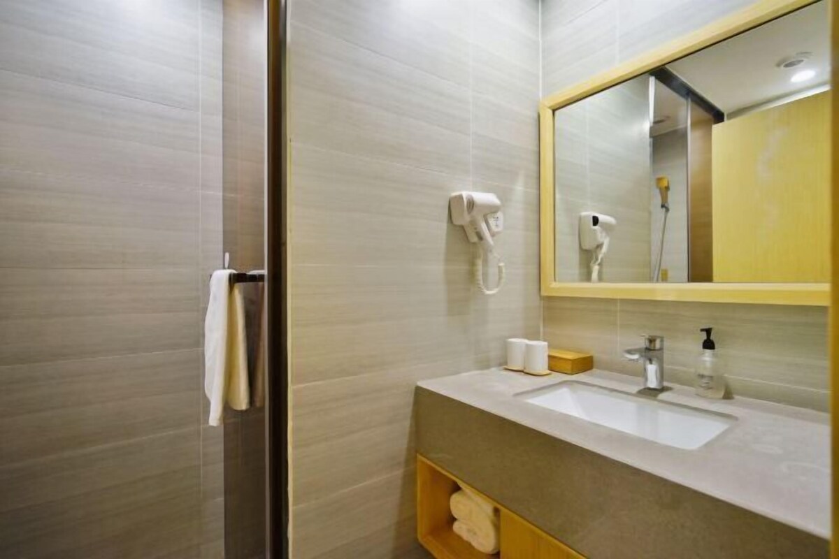 A modern bathroom with a glass shower enclosure, a white sink with a mirror above it, and a towel rack.
