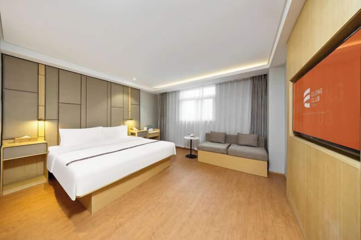 Habitació d'hotel moderna amb un llit gran, un sofà, una taula petita i una televisió.