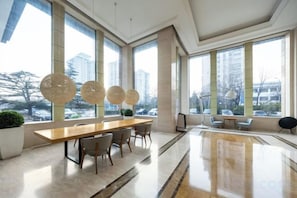Un espace de salle à manger moderne avec une longue table, des chaises et des luminaires suspendus.