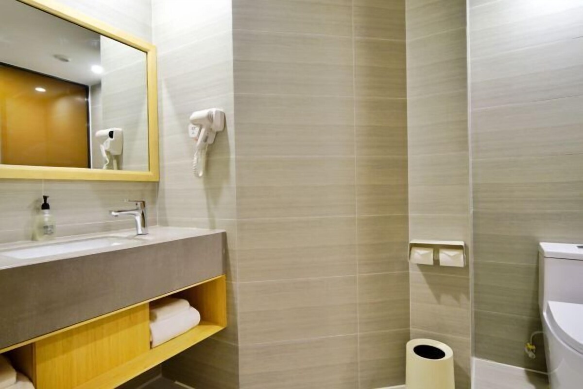 A modern bathroom with a large mirror, a sink, a towel rack, and a toilet.