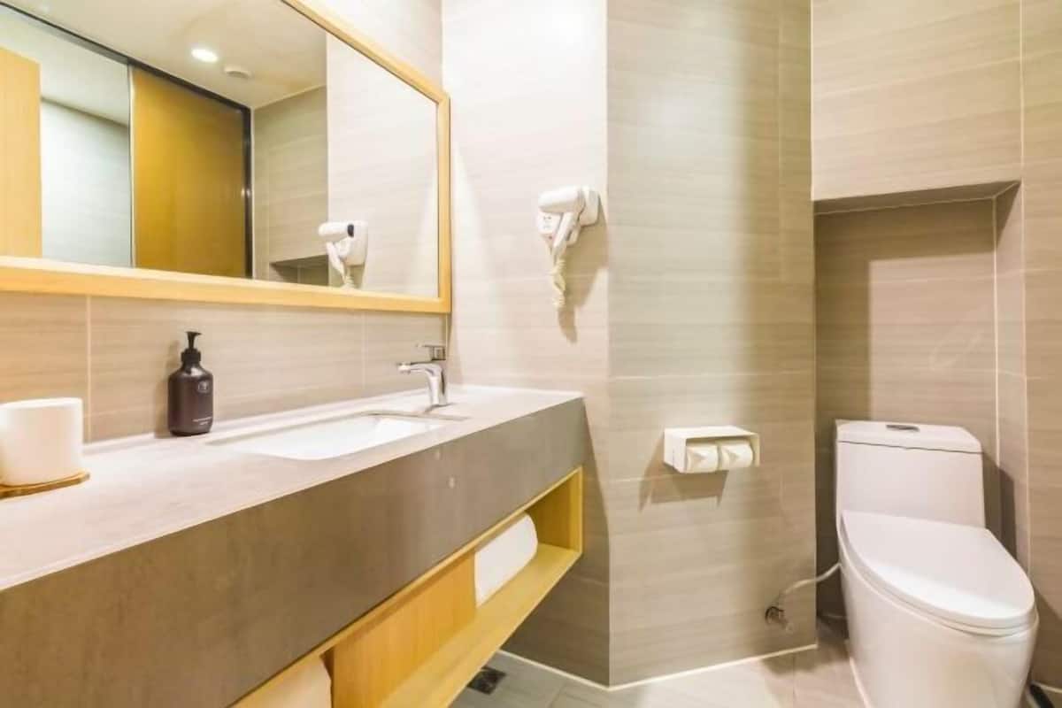 Un bany modern amb un mirall gran, un lavabo, una tassa i un dispensador de tovalloles.