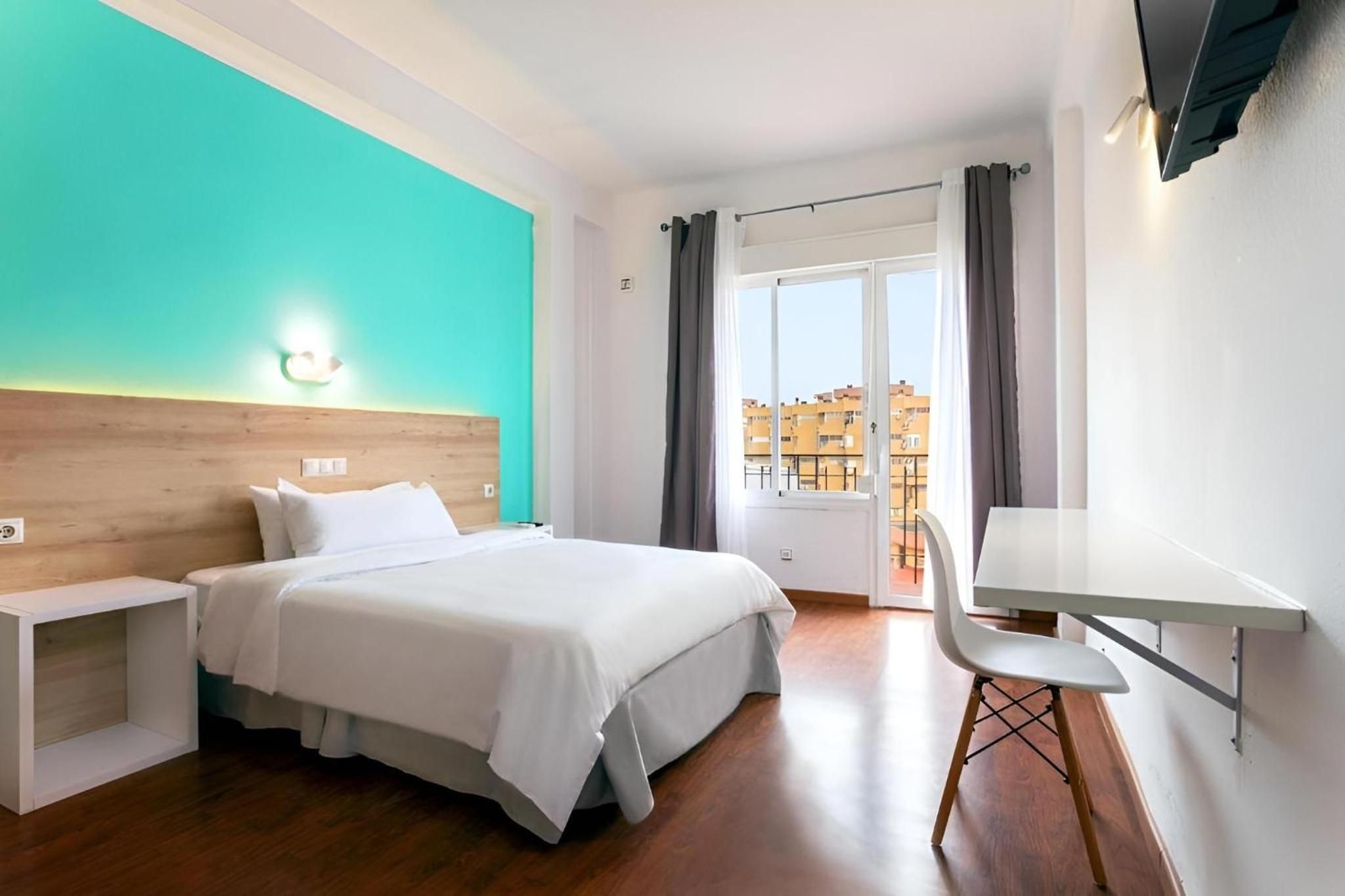 A hotel room with a bed, bedside tables, a desk, and a chair.