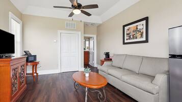 A living room with a wooden coffee table, a sofa, a television, and a ceiling fan.