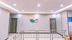A hotel lobby with a modern design, featuring a central staircase, two doors, and a wall-mounted artwork. - Jingzhou Orange Flower Boutique Hotel (Shashi Tiandi Branch) (Jingzhou)