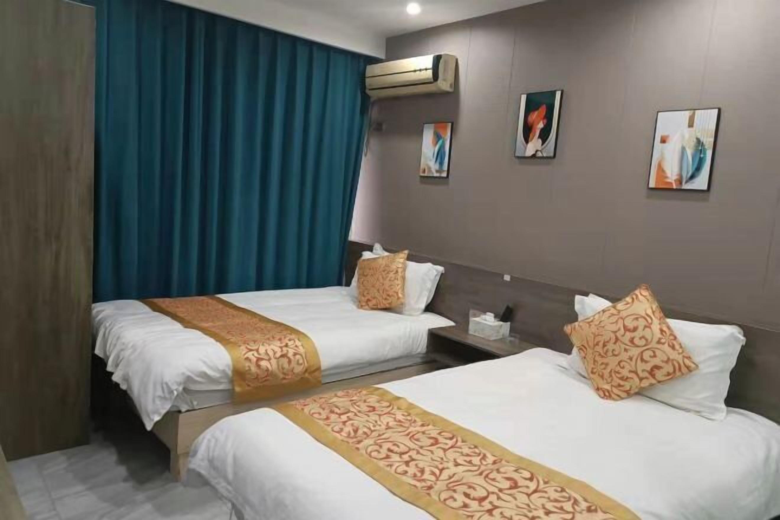Habitación de hotel con dos camas, cada una con una colcha estampada y almohadas a juego. Hay una mesita de noche con una lámpara y una caja de pañuelos, además de una obra de arte en la pared.