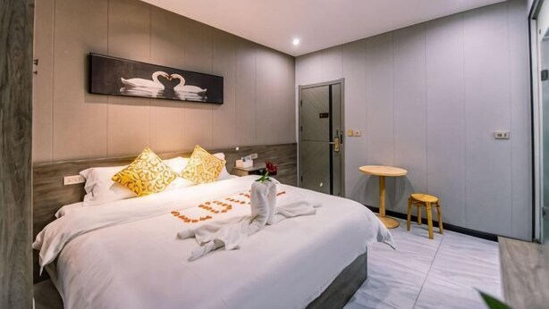 A modern hotel room with a large bed, a small round table, a door, and a wall-mounted artwork. - Jingzhou Orange Flower Boutique Hotel (Shashi Tiandi Branch) (Jingzhou)