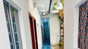 A narrow hallway with a blue floor, white walls, and a patterned wall on the right. - Hostal Quistococha  (Laraos)