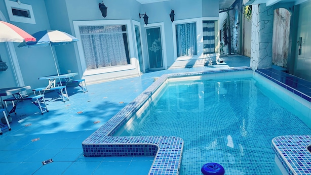A swimming pool with tiled edges and a blue floor, surrounded by walls and doors. - Hostal Quistococha  (Laraos)