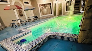 A swimming pool with a tiled edge, a hot tub, and a stone wall. - Hostal Quistococha  (Laraos)