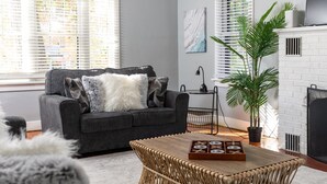 A living room with a grey sofa, a wooden coffee table, and a white fireplace.