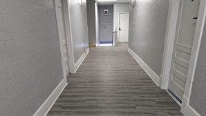 A hallway with grey walls and a grey wooden floor. - Studio with Queen Bed (Robinson)