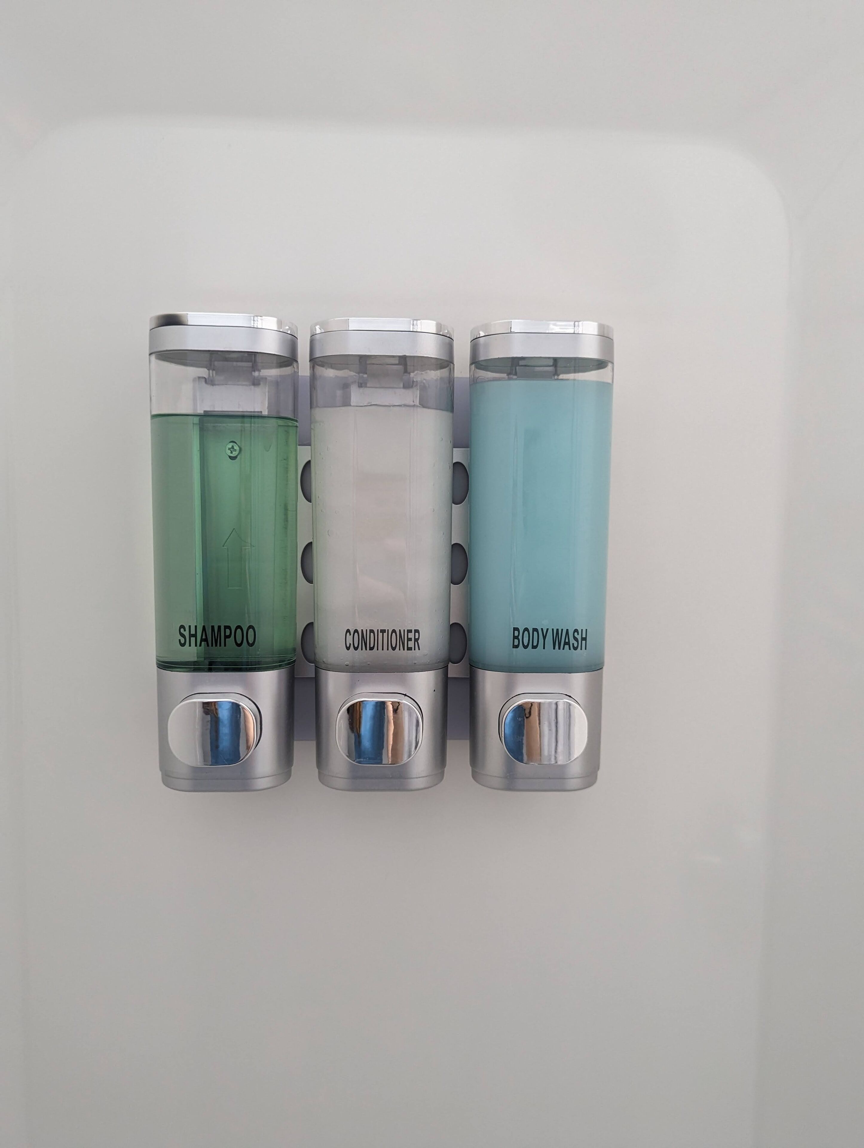 Trois récipients étiquetés « shampoing », « après-shampoing » et « gel douche ».