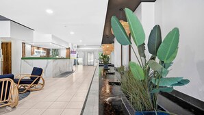 A hotel lobby with a reception desk, seating area, and a water feature. - Paradiso 3 Bedroom Ground Floor 108 (Kingscliff)