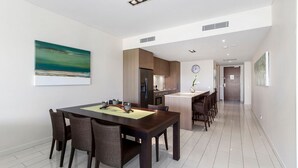 Eine moderne Küche mit Kühlschrank, Herd und Essbereich mit Stühlen und einem Tisch.