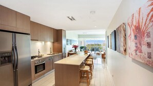 Une cuisine moderne dotée d’un îlot central, d’appareils électroménagers en acier inoxydable et donnant sur un patio extérieur.