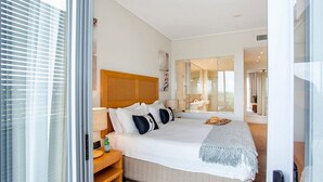 Une chambre d’hôtel moderne avec un grand lit, une table de chevet, un miroir et une vue sur la salle de bain.