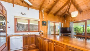 A wooden interior with a kitchen, a dining area, and a TV. - Deckhouse Surfside - Spacious Family Home with Beach Access (Pottsville)