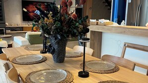 Un coin repas avec une table en bois, dressée avec des assiettes et agrémentée d’un centre de table.