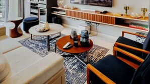 Un salon moderne doté d’un grand téléviseur à écran plat, de sièges confortables, d’une table basse et d’une cheminée.