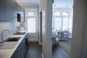 A modern kitchen with grey cabinets, a sink, and a dining area with a table and chairs.