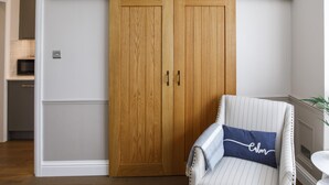 Une pièce avec une armoire en bois, un fauteuil à rayures et une petite table blanche.